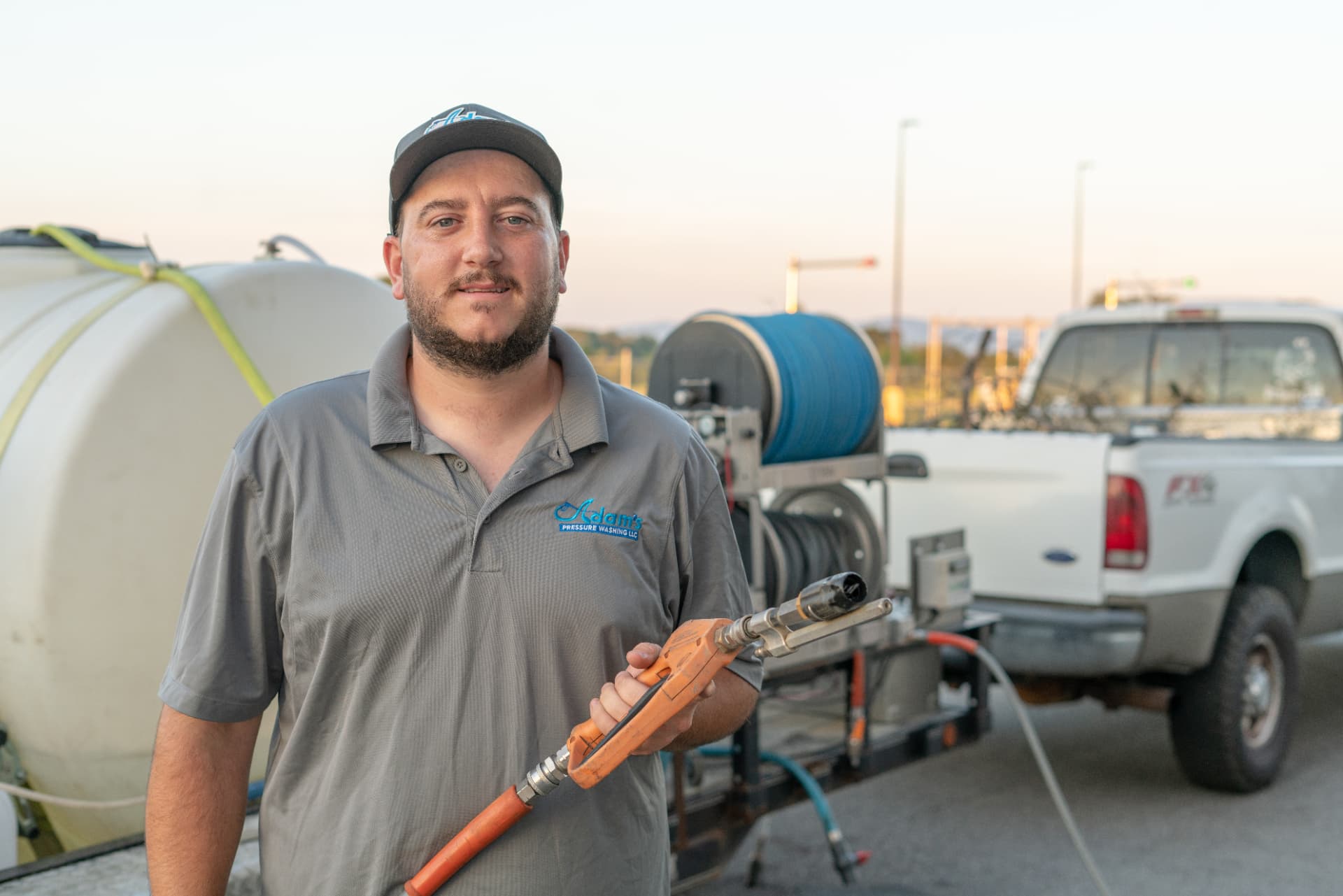 Adam, owner of Adam's Pressure Washing, with his rig and truck at sunrise