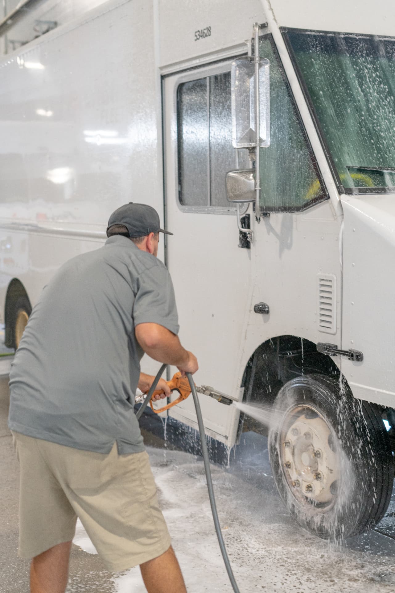 Worker washing the cab and windshield of a delivery truck