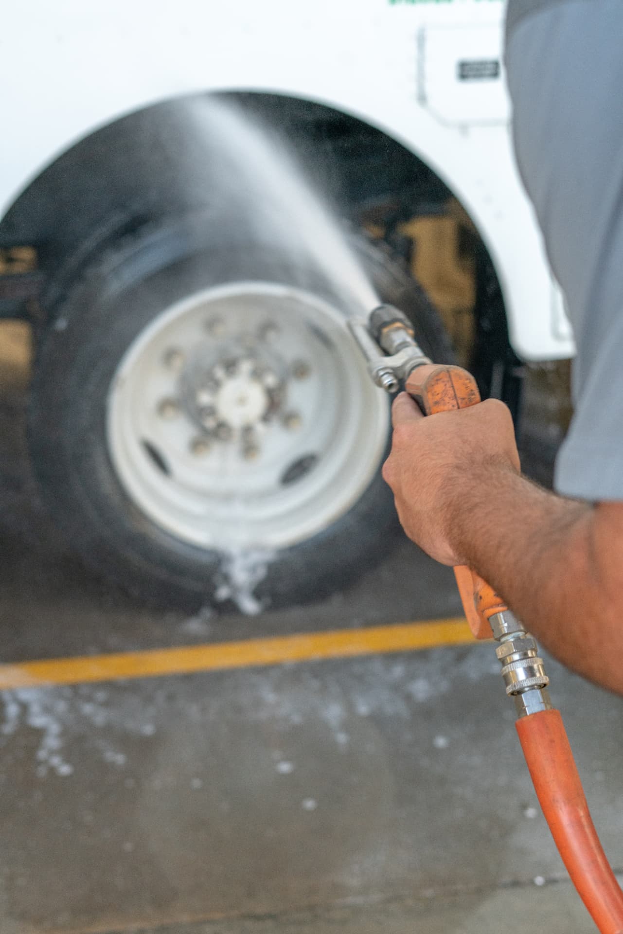 Close-up of a pressure washer spraying a truck wheel and tire