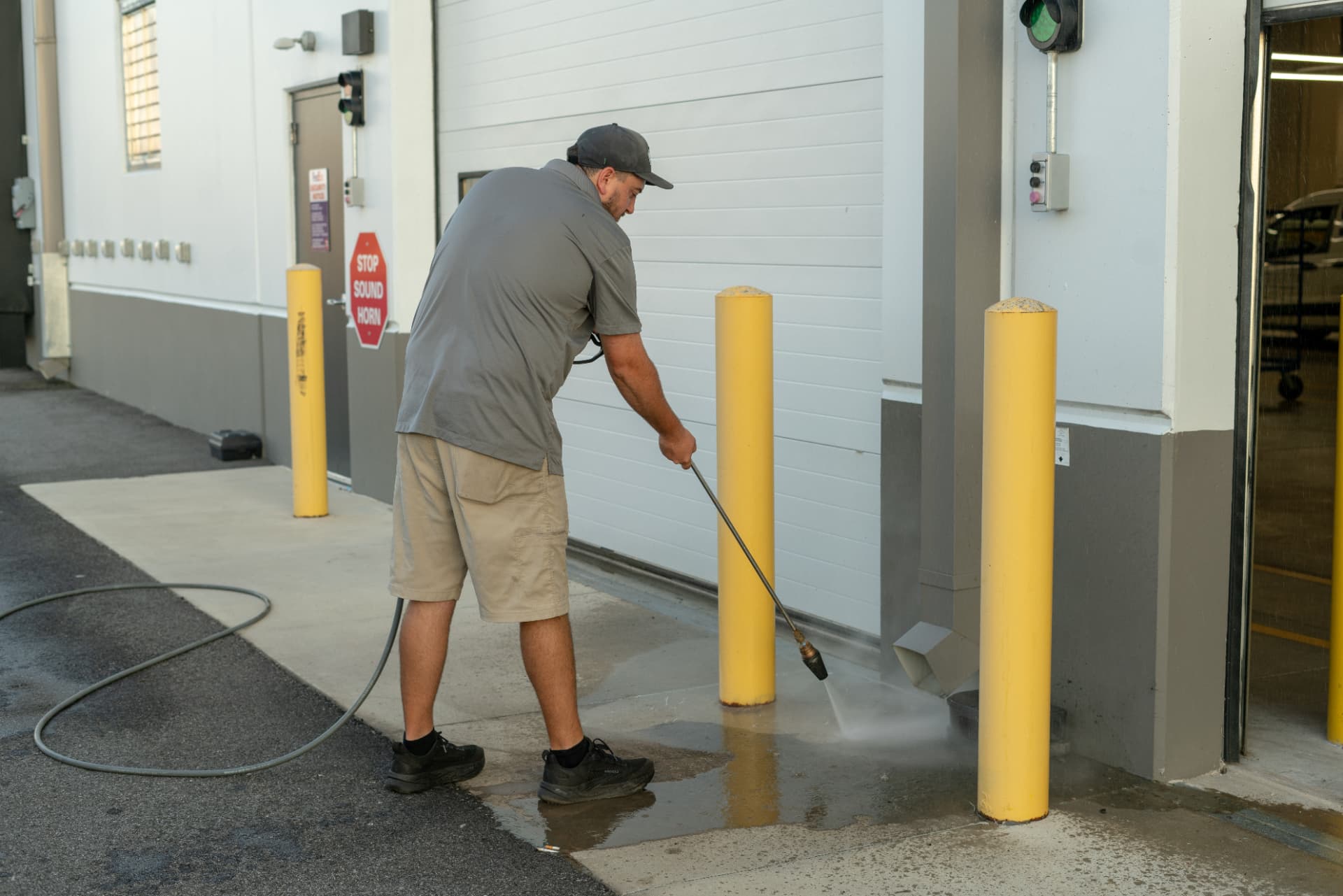 Worker pressure washing concrete beside a commercial warehouse dock