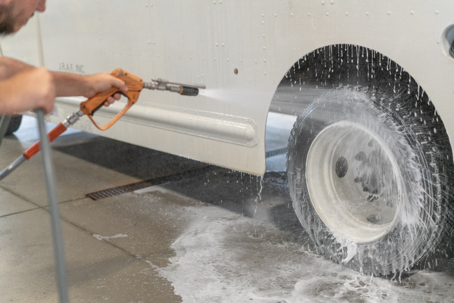 Close-up of a truck tire and white rim being pressure washed