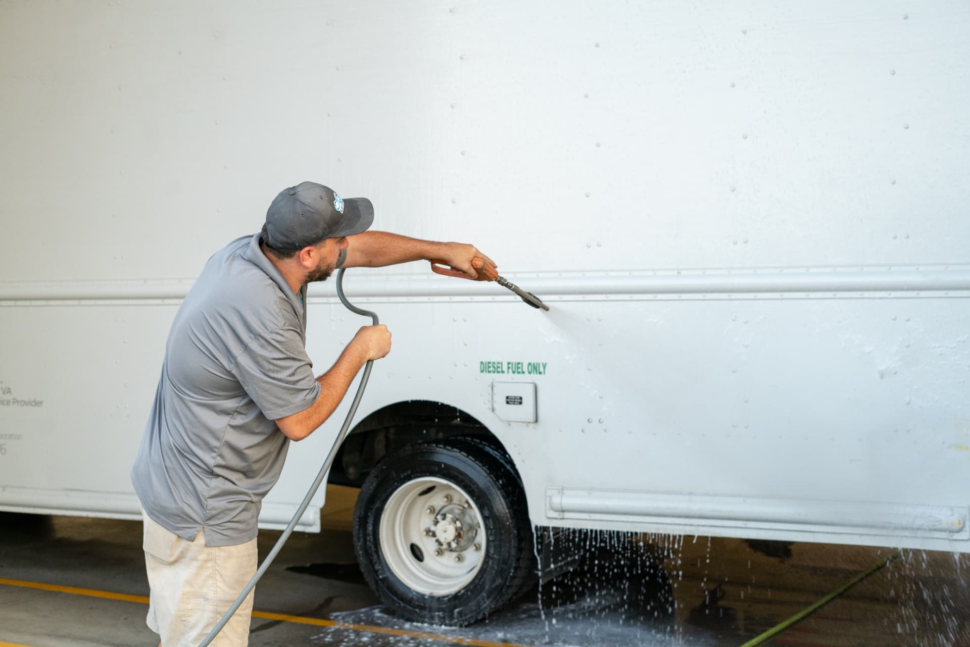 Worker washing the white side panel of a delivery truck