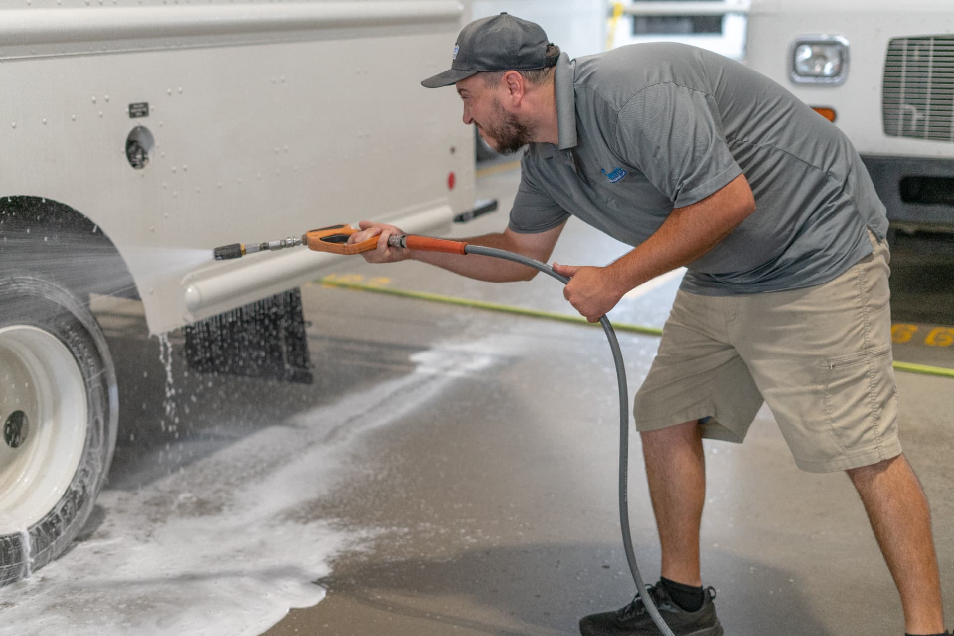 Worker washing the lower rocker panel of a box truck