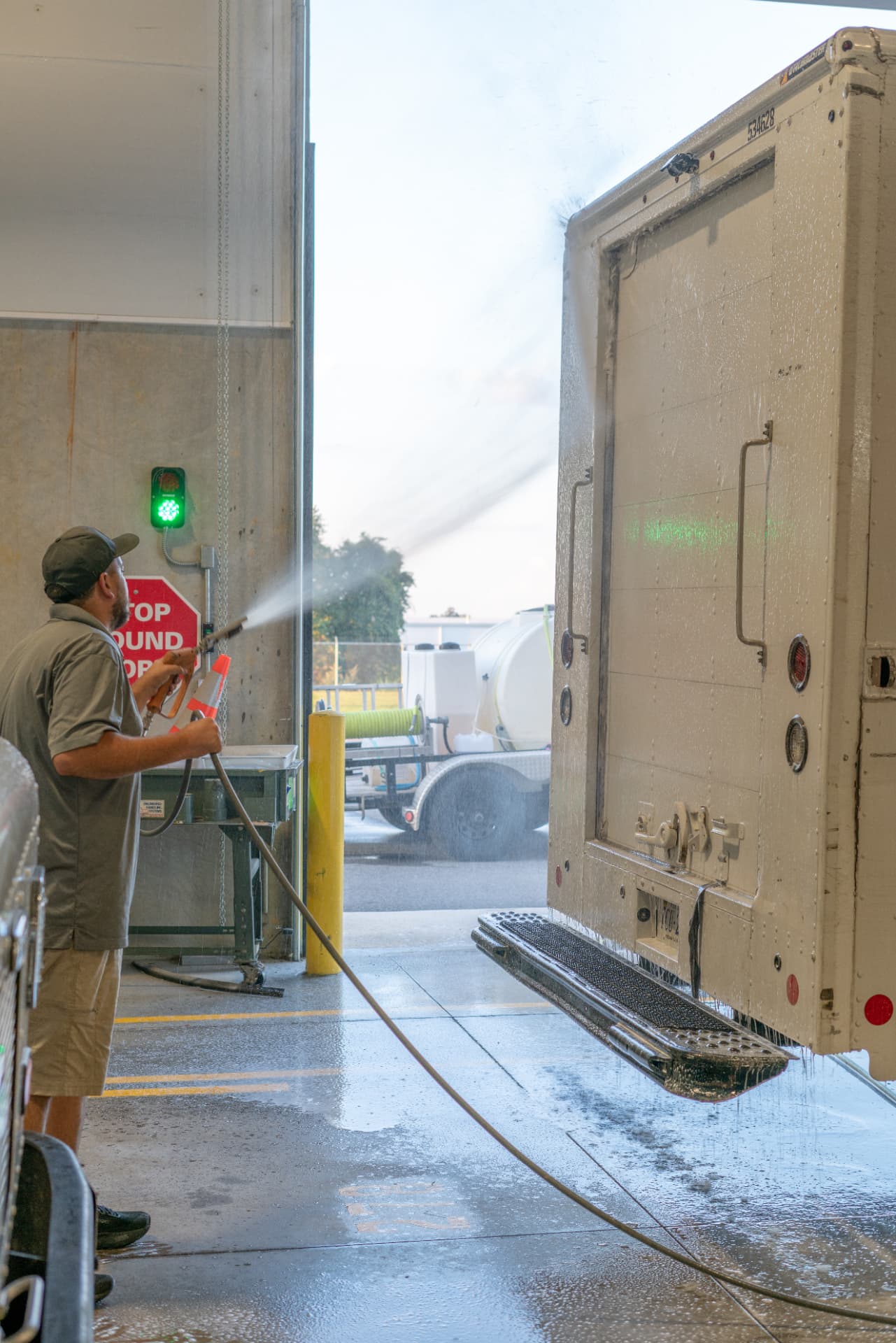 Worker spraying the rear doors and step of a delivery truck